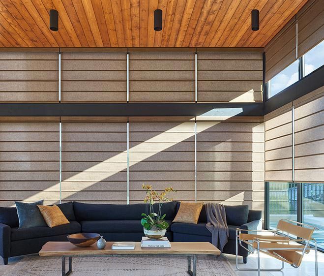 A living room with a black sectional couch and a wooden ceiling