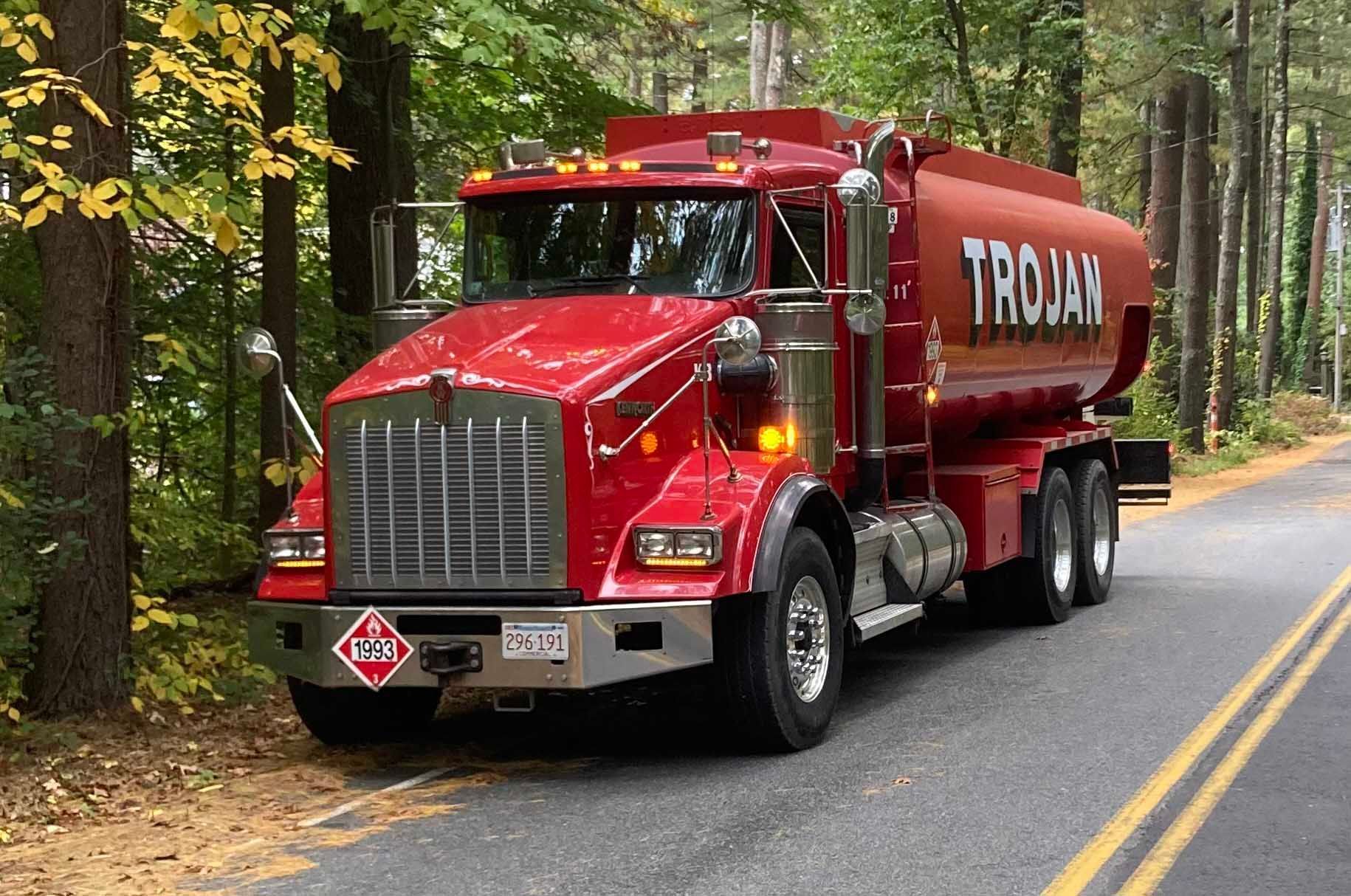 Red tanker truck driving on a forest road with yellow center lines