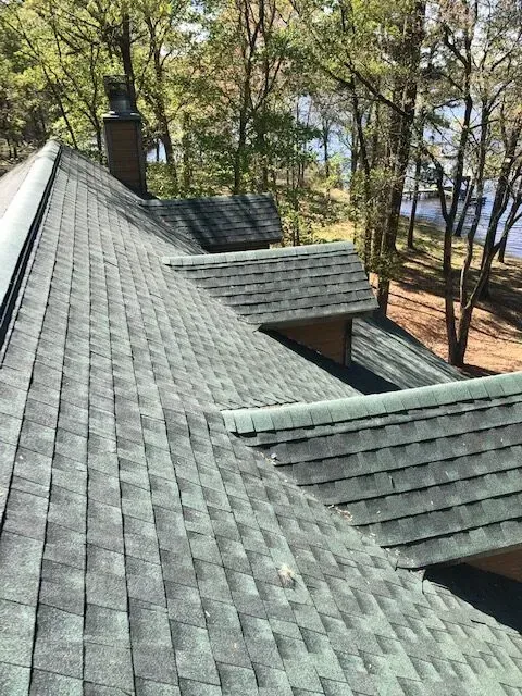 A roof of a house with a view of a lake and trees.