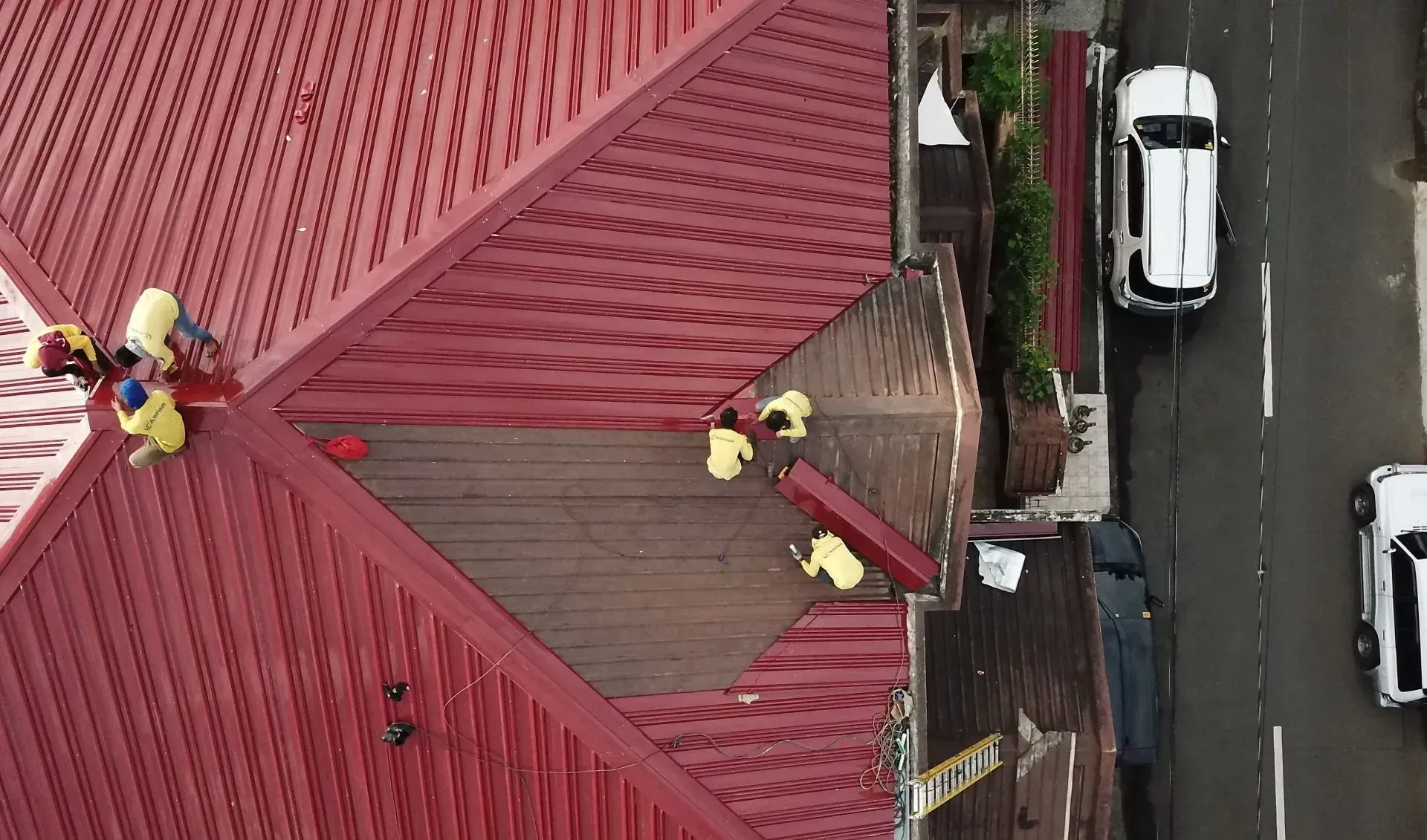An aerial view of a building with a red roof and a car driving down the street.