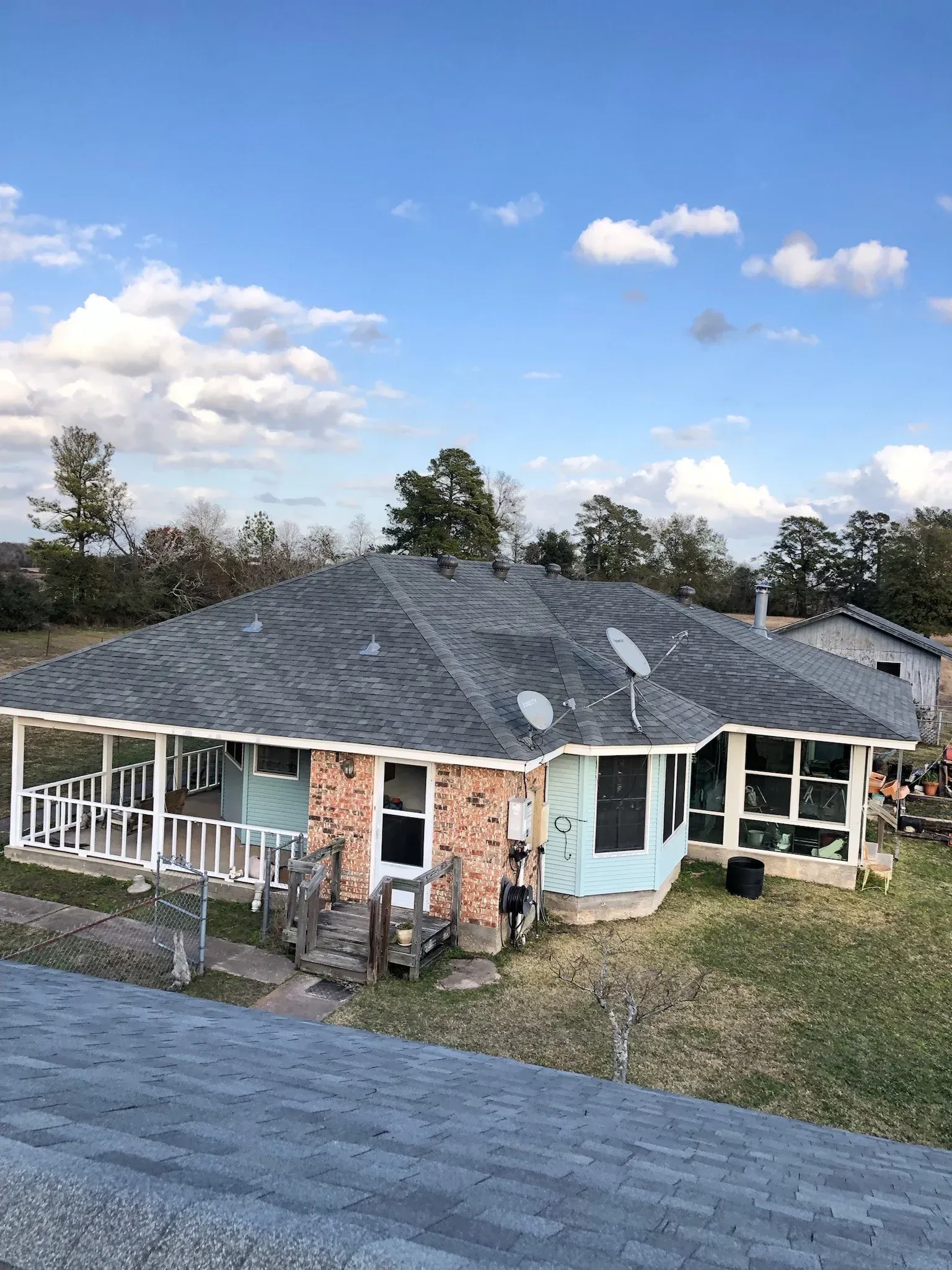 A house with a gray roof and a porch on a sunny day.