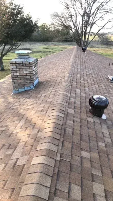 A roof with a chimney and a fan on it.