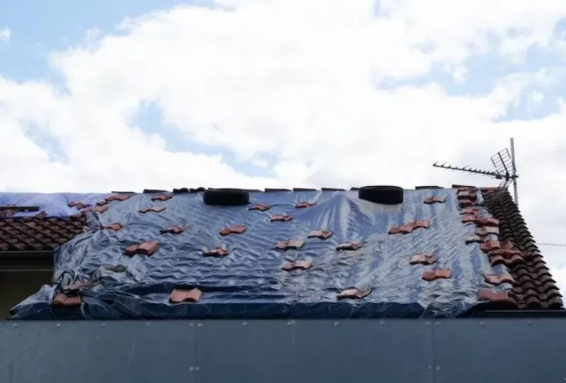 The roof of a building is covered in plastic and tiles.