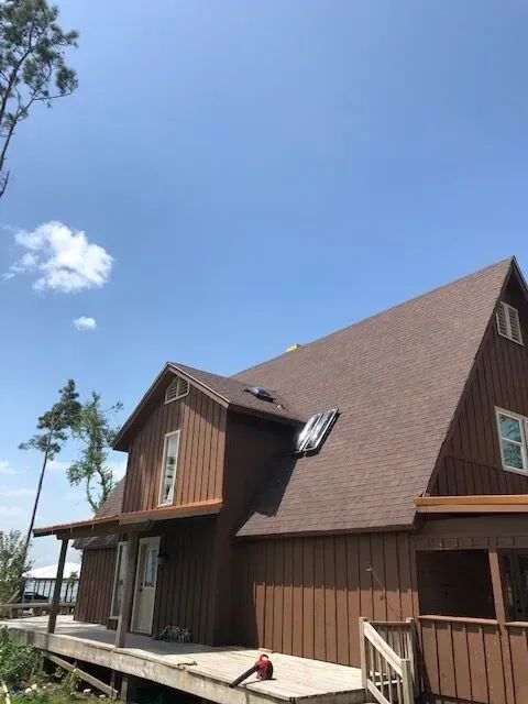 A brown house with a brown roof and a blue sky in the background.