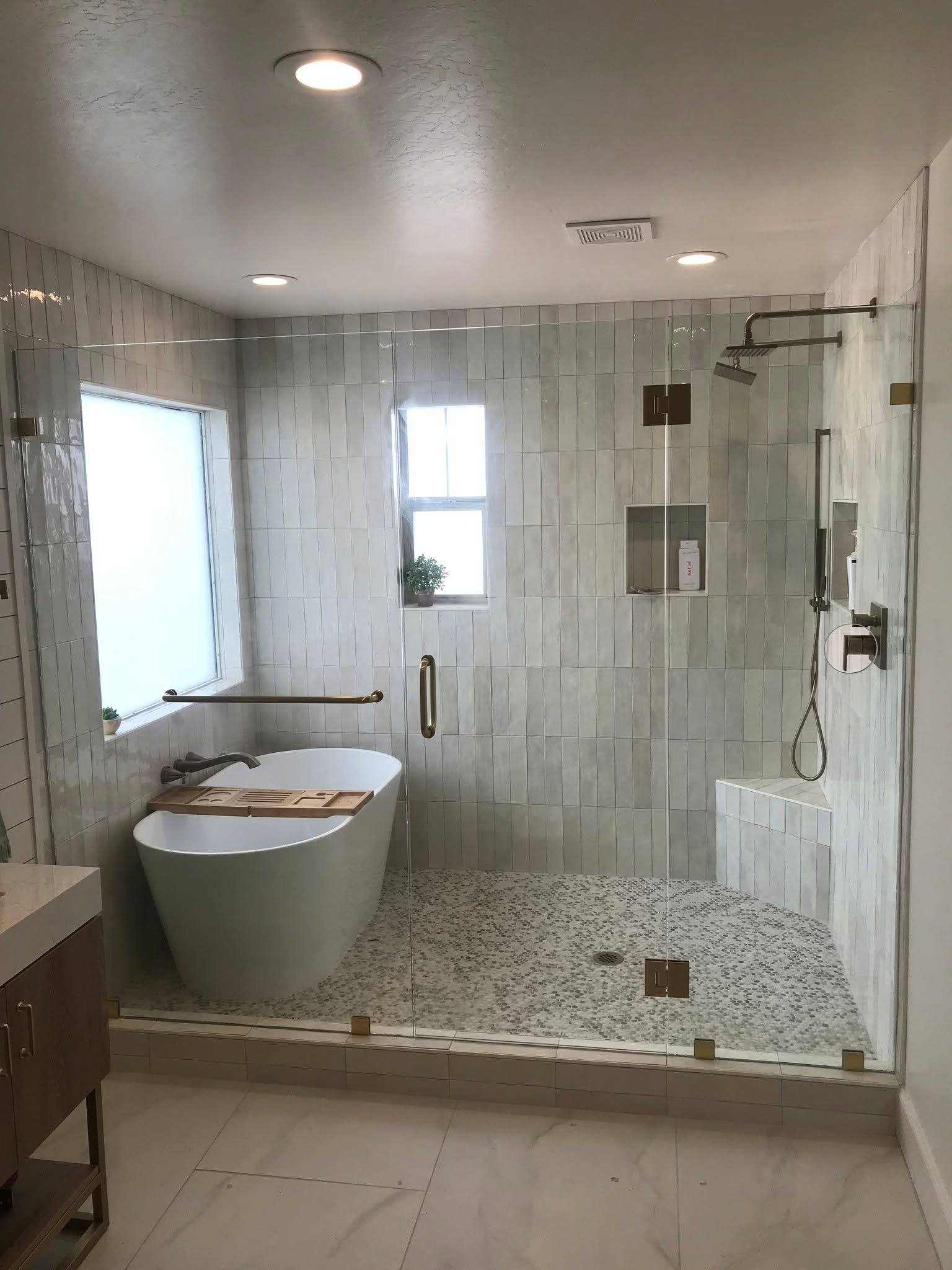 Modern white bathroom with freestanding tub, glass shower, and tiled floor.