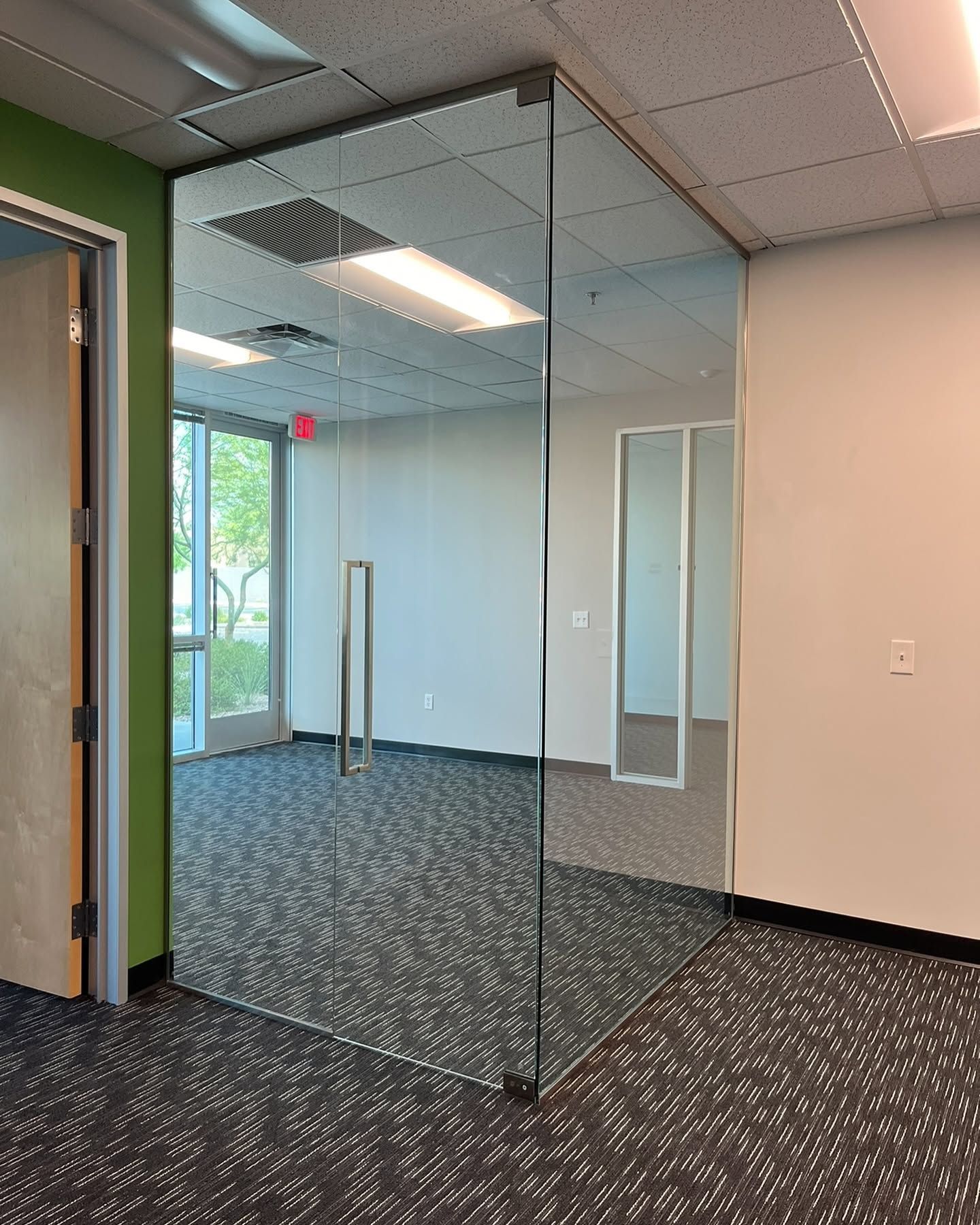Glass office partition with double doors in an empty carpeted conference room.