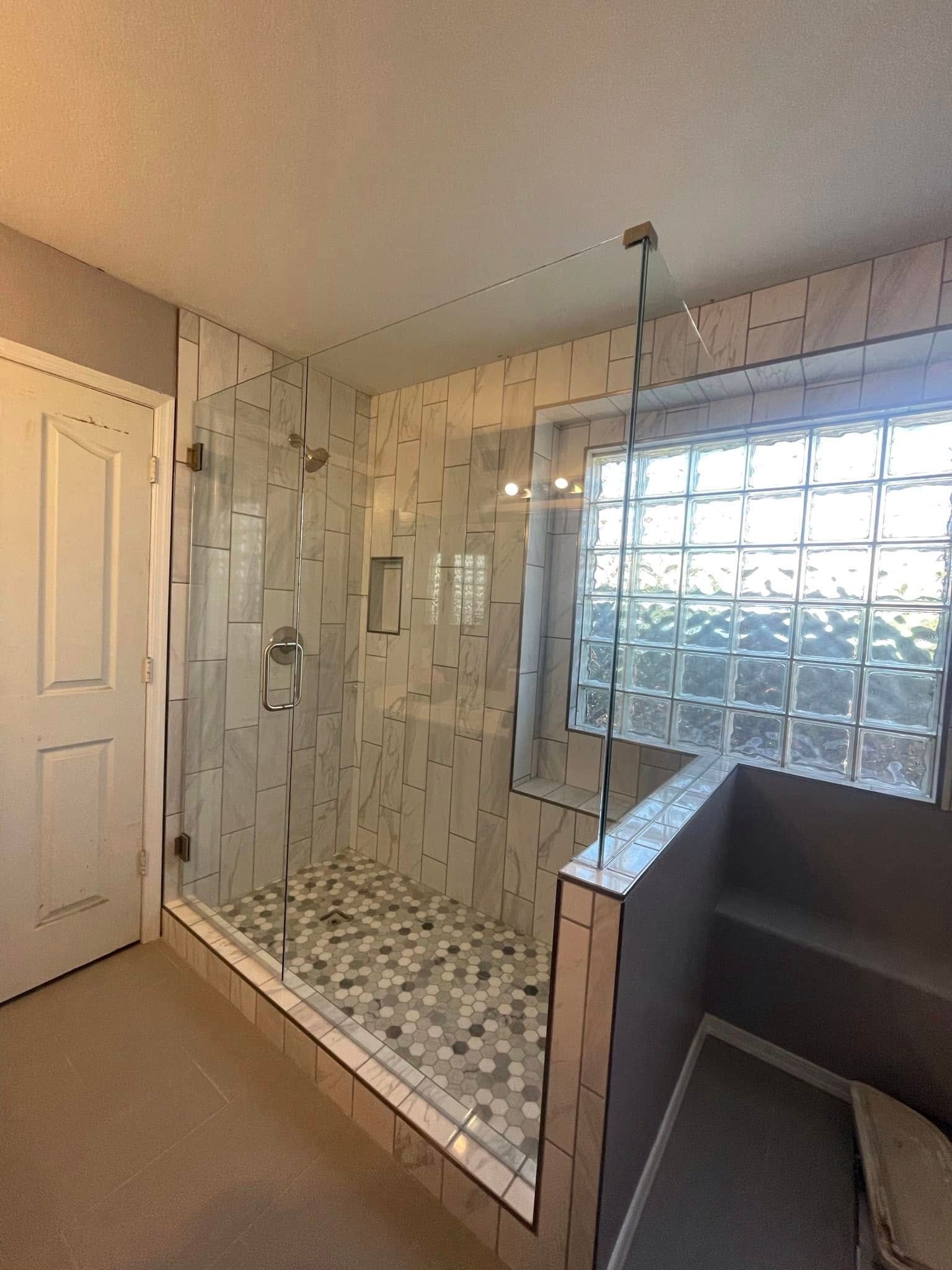 Empty bathroom with a glass-enclosed shower, tiled walls, and a glass-block window.