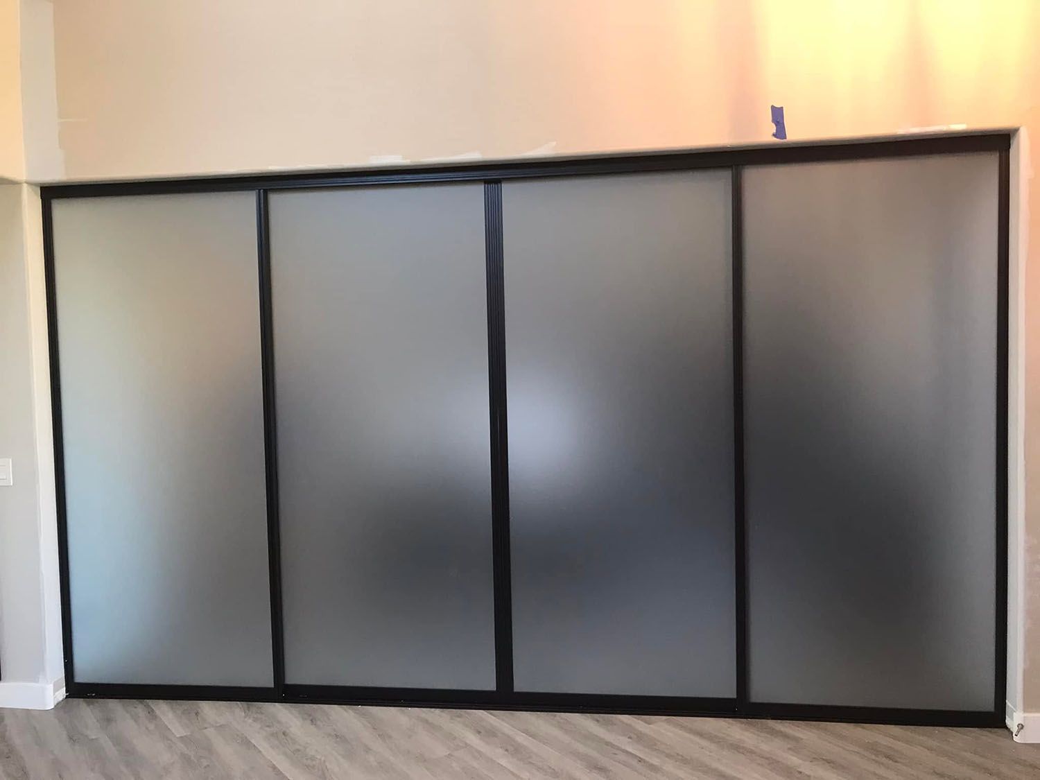 Large frosted glass sliding partition with black frame in a room.