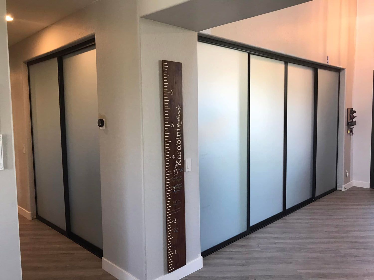 Modern office hallway with frosted glass conference room walls and wood flooring.
