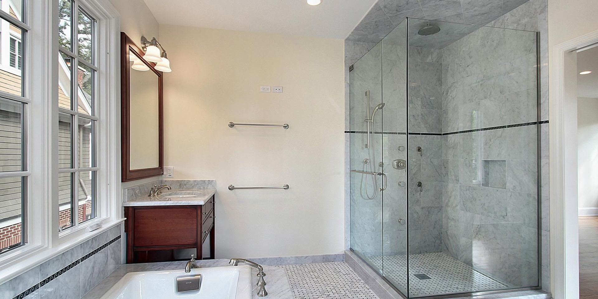 Modern bathroom with glass shower, vanity, and large windows letting in natural light.