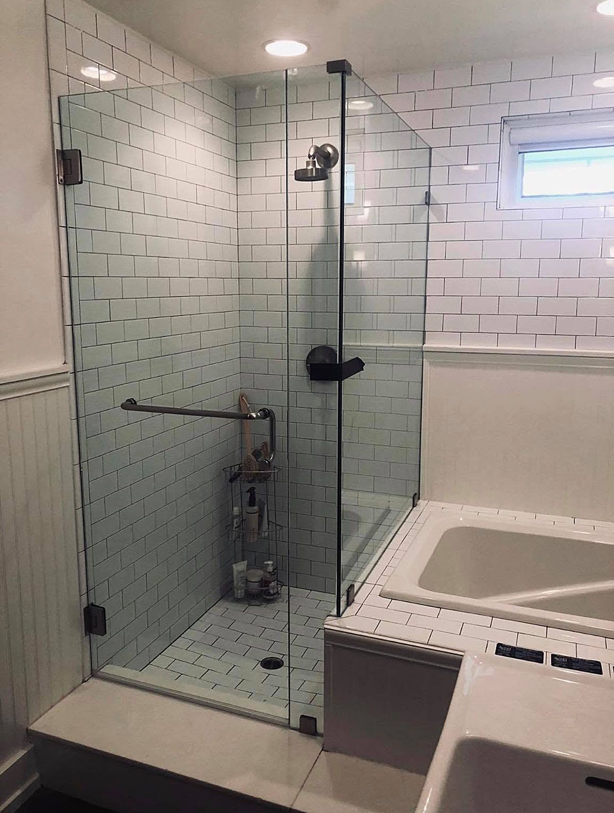Modern bathroom with glass walk-in shower, white tile, and built-in soaking tub.