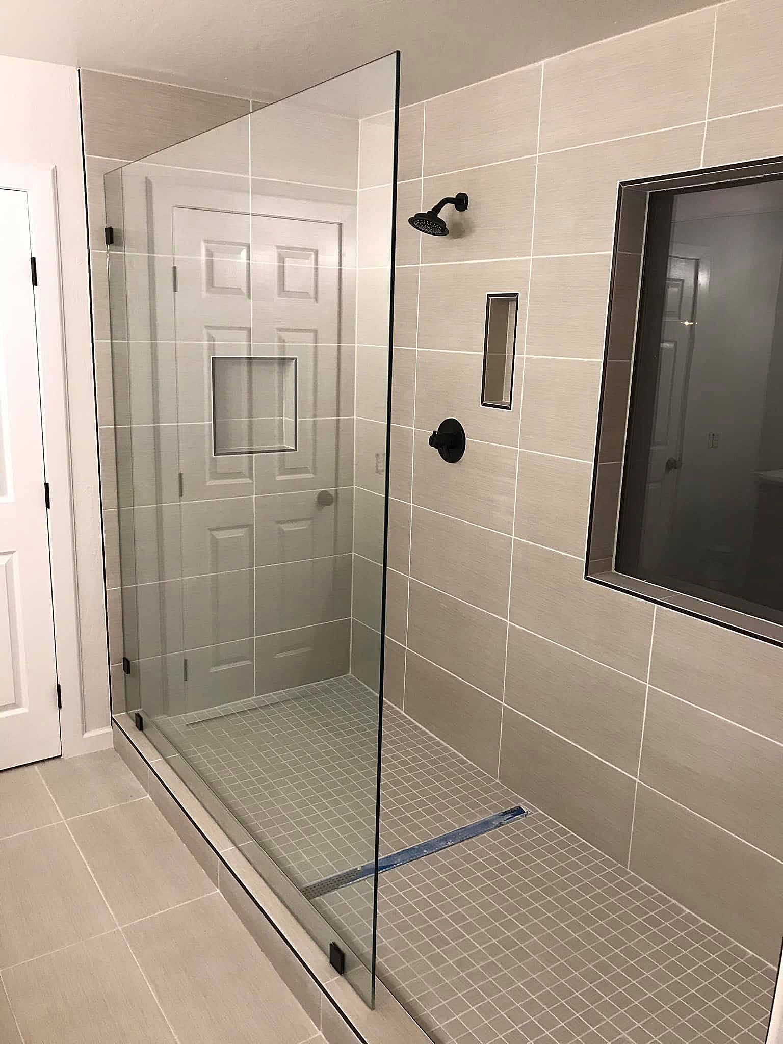 Bathroom with glass-enclosed walk-in shower, tiled walls, and pebble-textured shower floor.