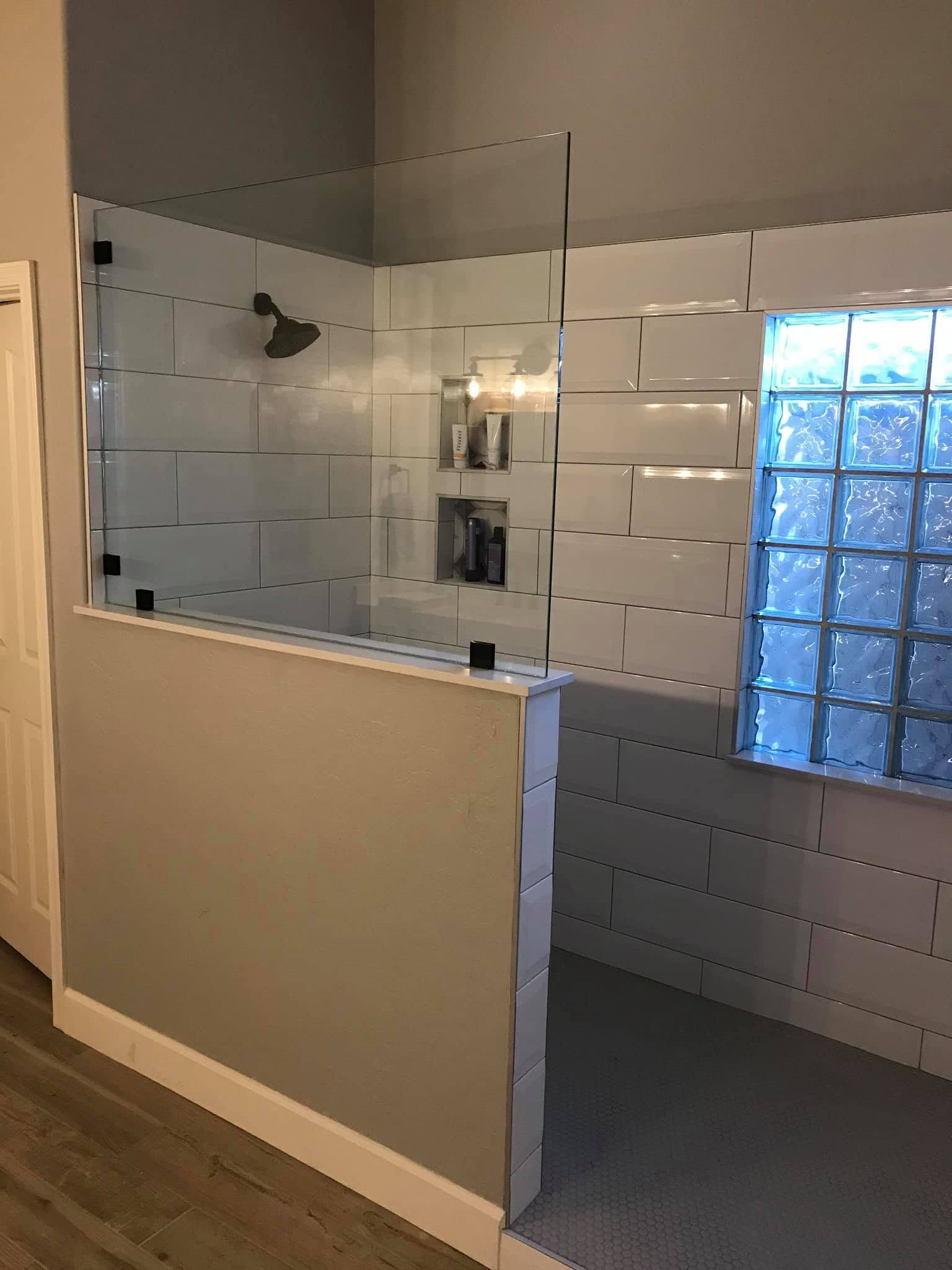 Bathroom with glass-tile shower walls, a half-height partition, and a frosted glass block window.
