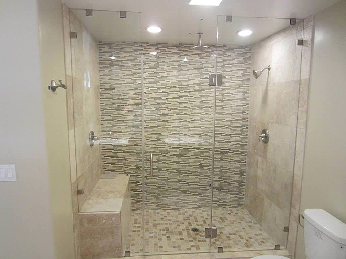 Modern bathroom with glass-enclosed shower, beige stone tile, and a built-in bench.