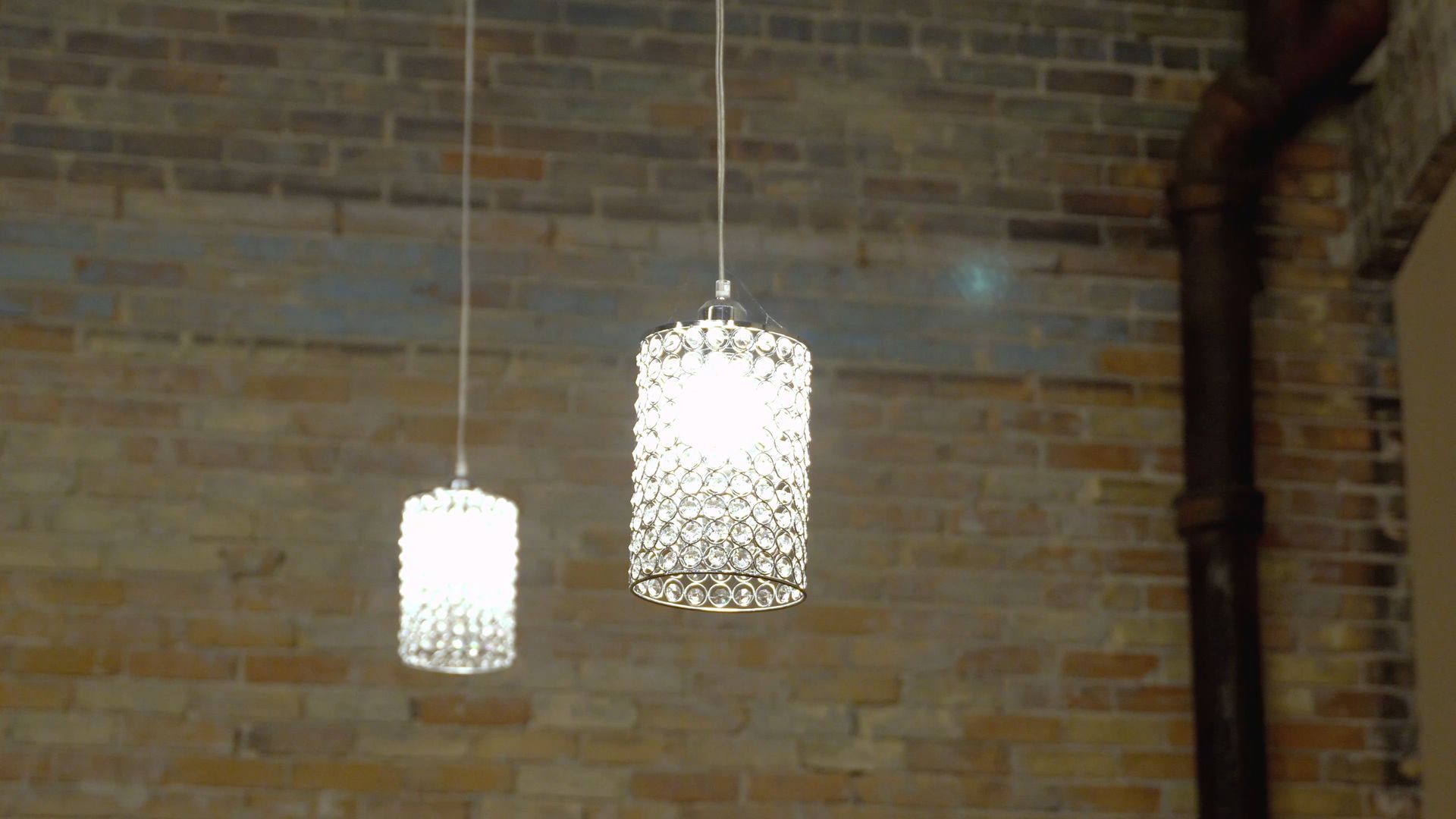 Two hanging white pendant lights glow against a brick wall in an industrial-style interior.