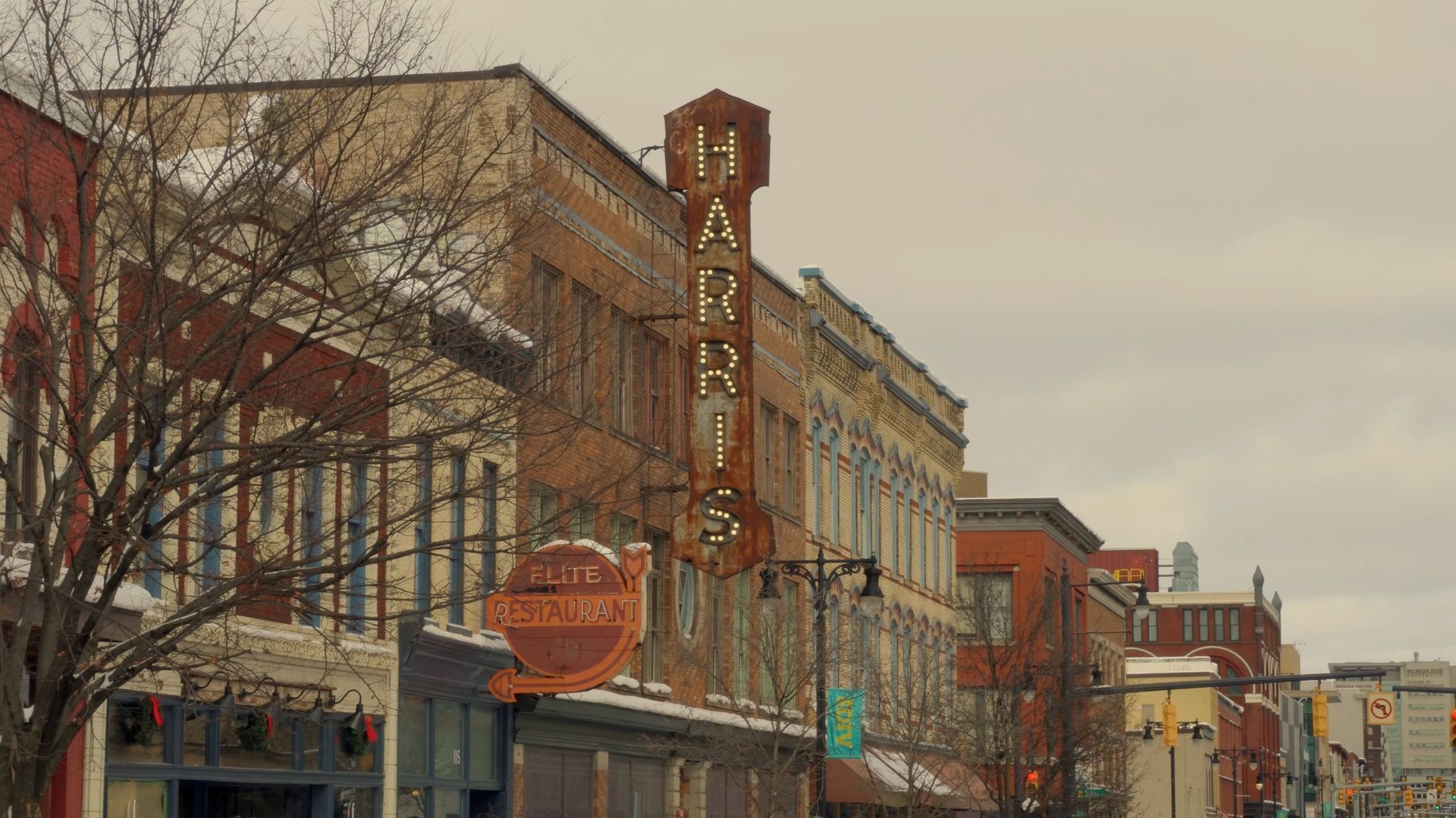 Historic downtown street with brick storefronts and a vertical theater sign under an overcast sky.