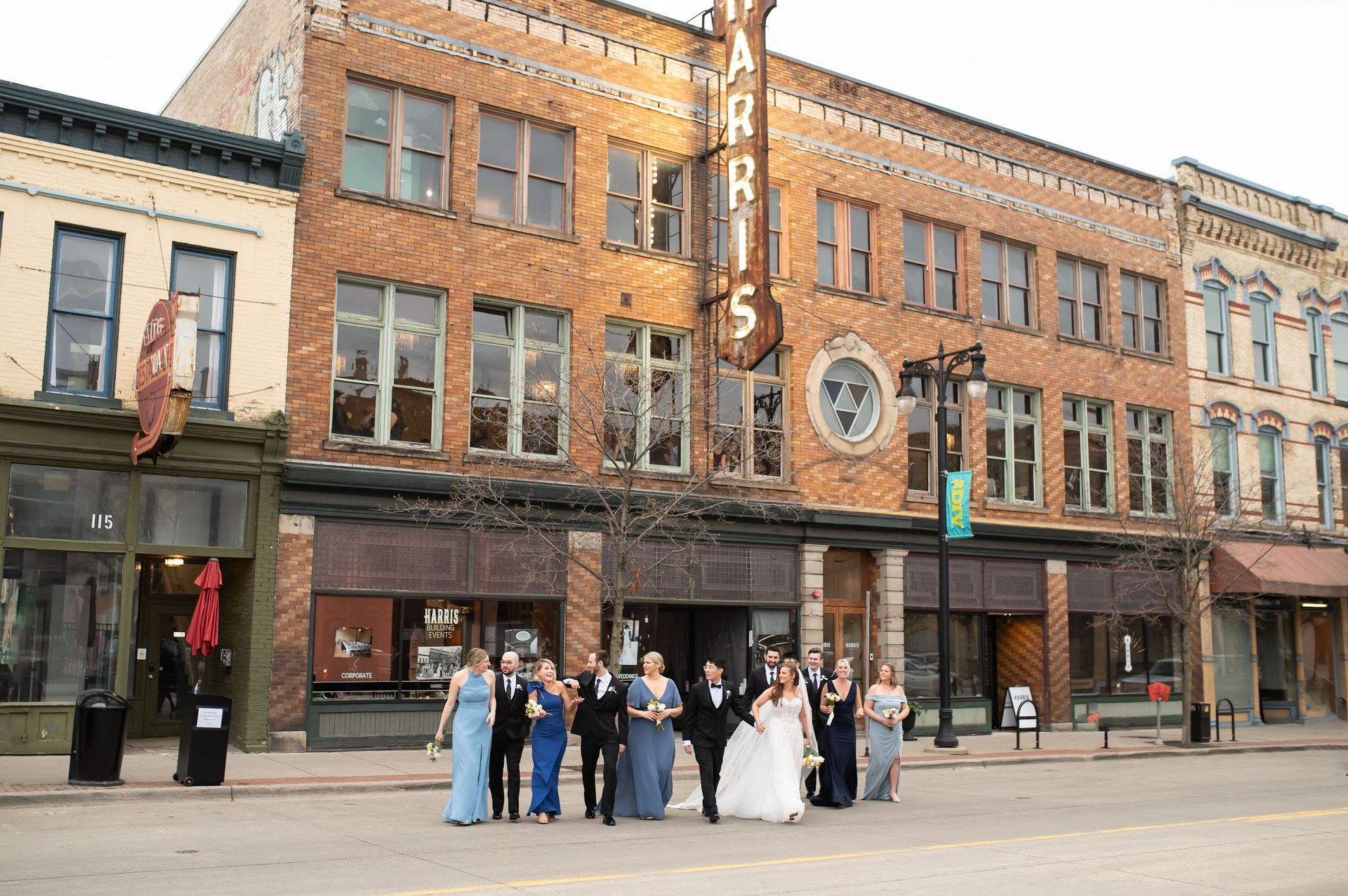 Wedding party posing outside a brick theater with a large vertical marquee sign.