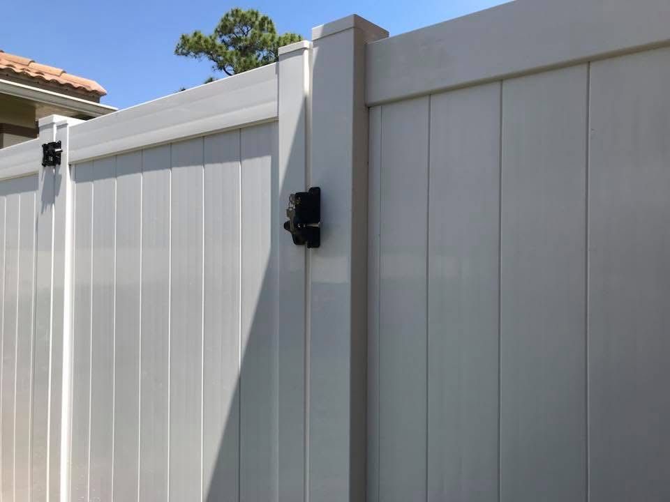 A white vinyl fence with a gate attached to it.