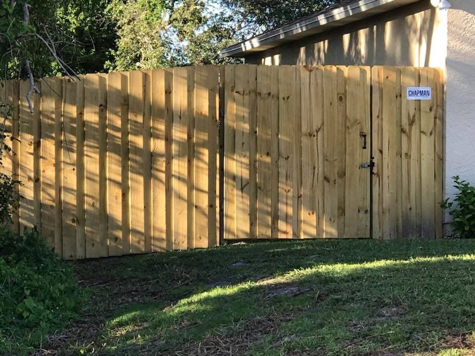 A wooden fence with a gate in front of a house.