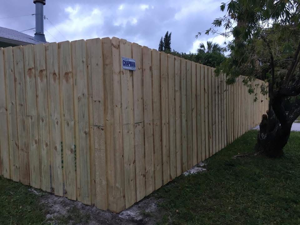 A wooden fence is sitting in the grass next to a tree.