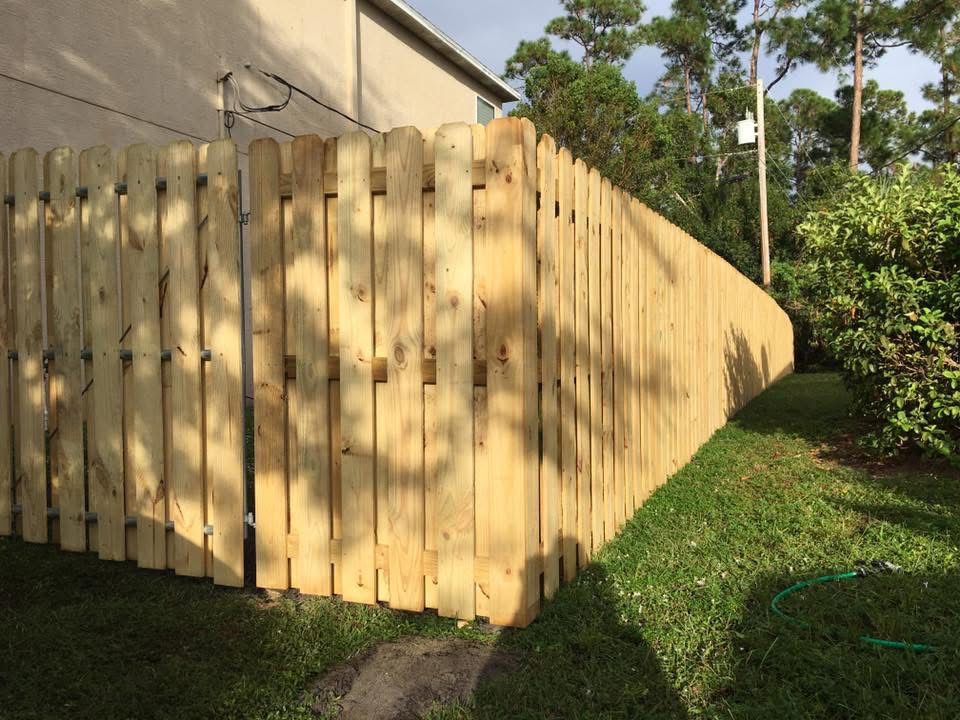 A wooden fence is sitting in the grass next to a house.