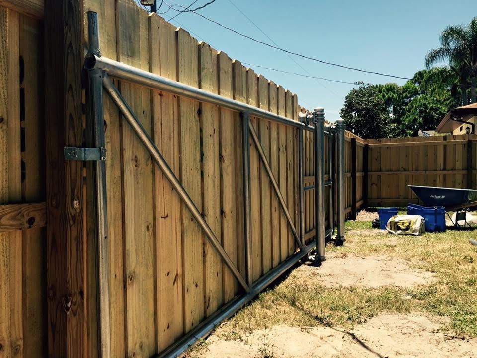 A wooden fence with a sliding gate in the backyard.