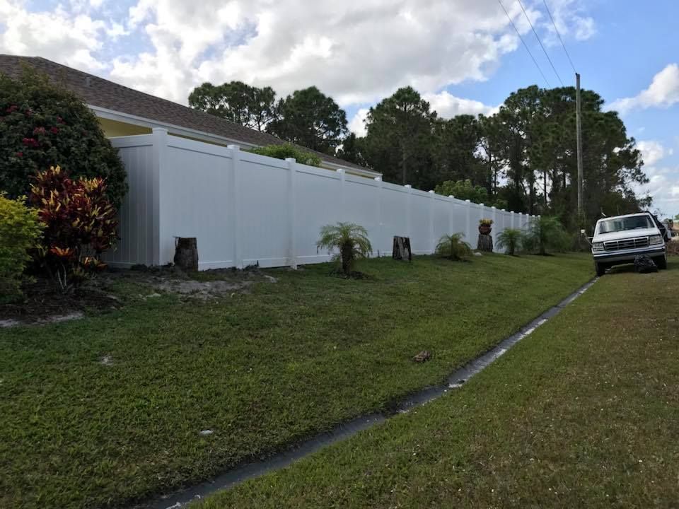 A white truck is parked in front of a white fence.