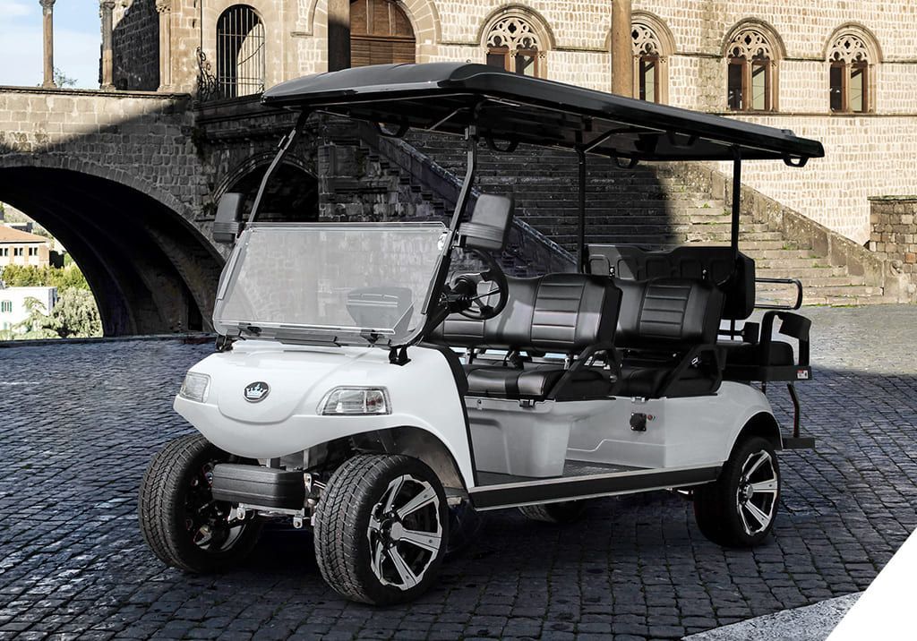 Golf cart on a green fairway with a pond, trees, and bright sky.
