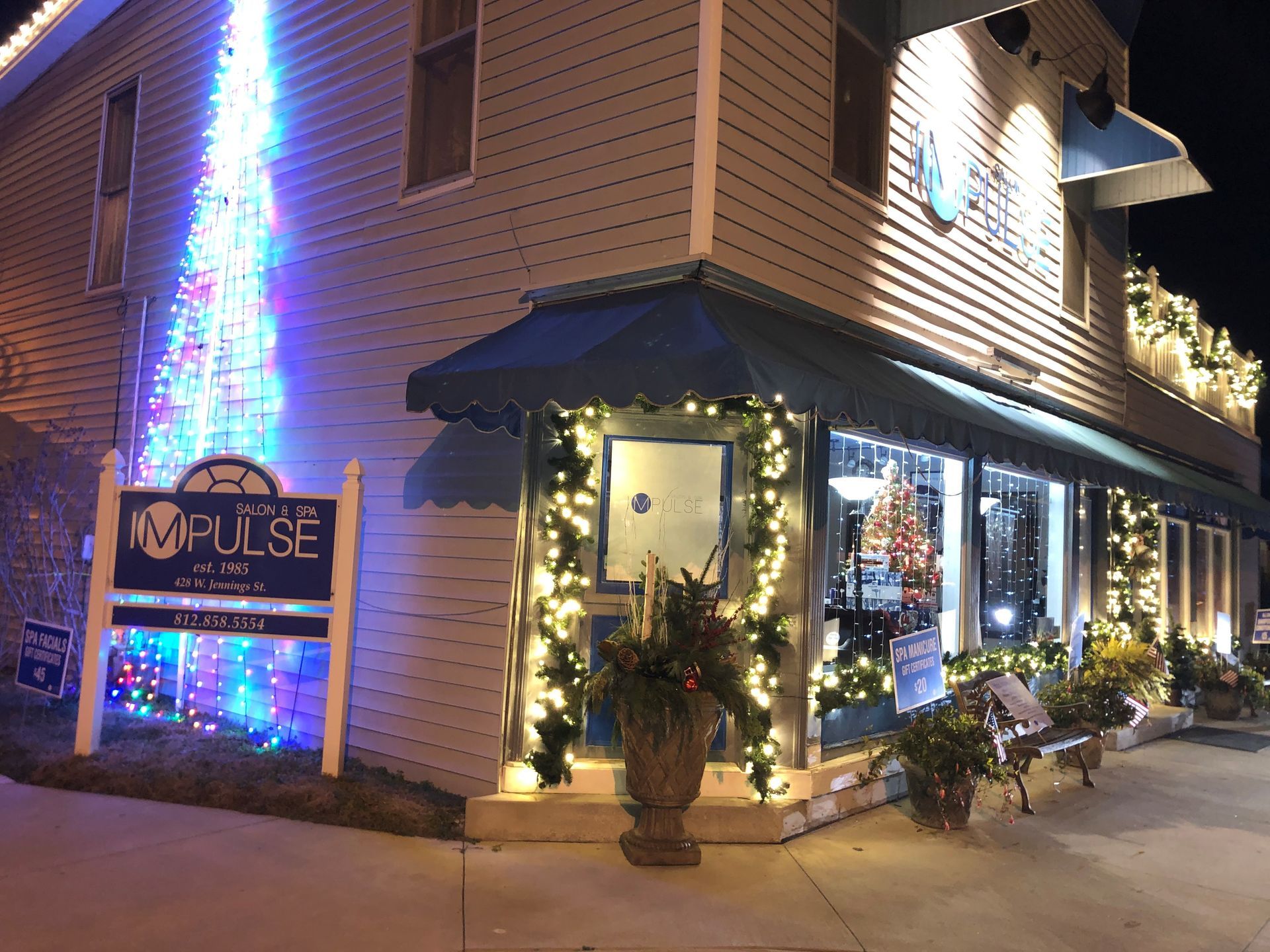 Lit storefront at night with holiday lights, wreaths, and a sign reading “PULSE”