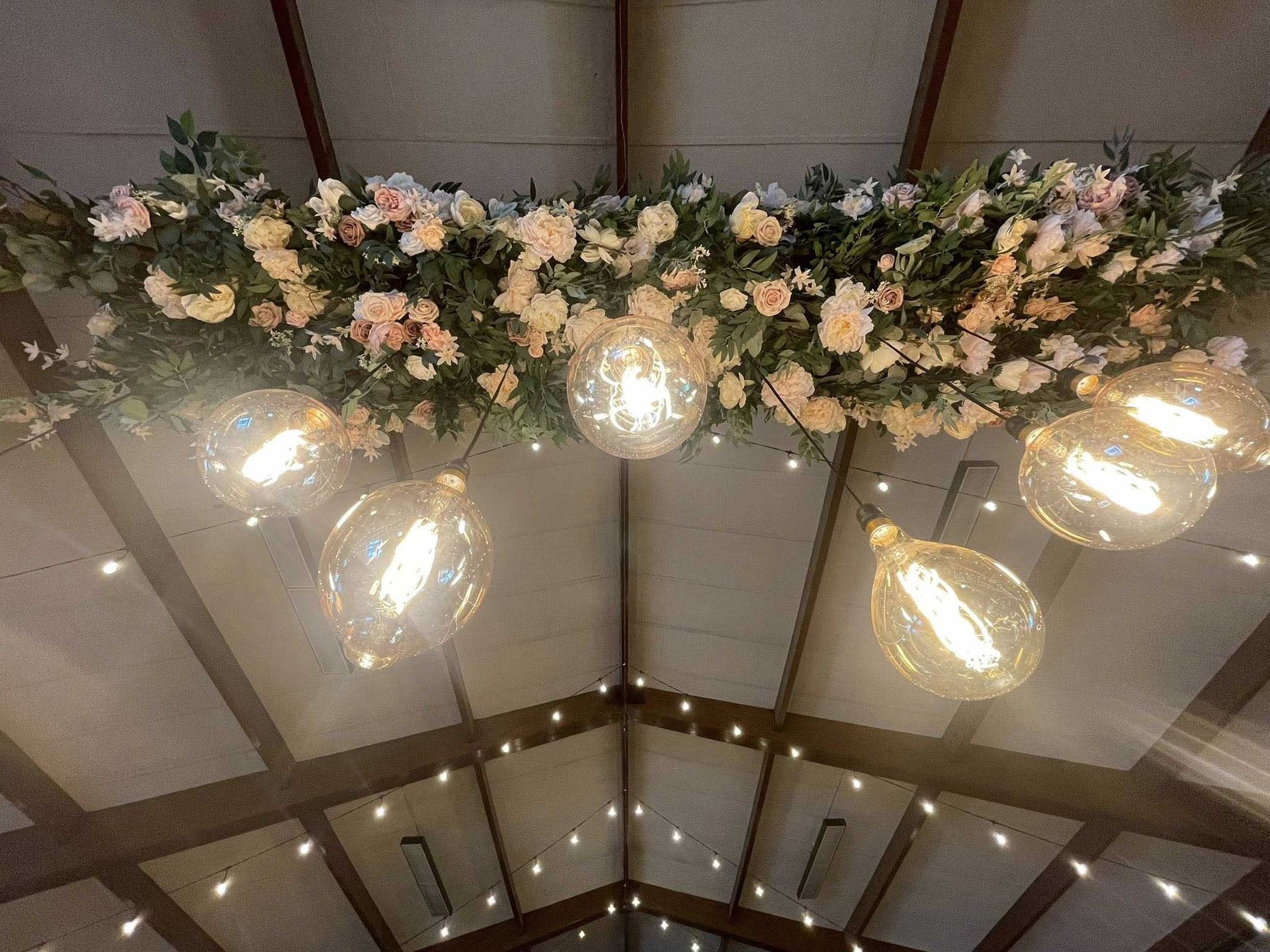 Ceiling decorated with flowers and hanging lightbulbs, fairy lights.