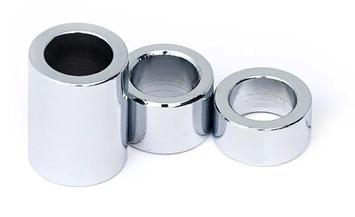 Three shiny chrome cylindrical caps or spacers arranged in a row on a white background