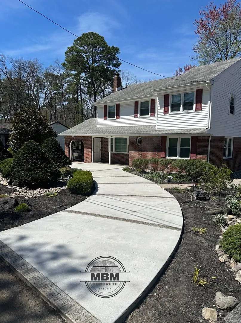 Curving concrete walkway leading to a two-story white house with red shutters, surrounded by landscaping.