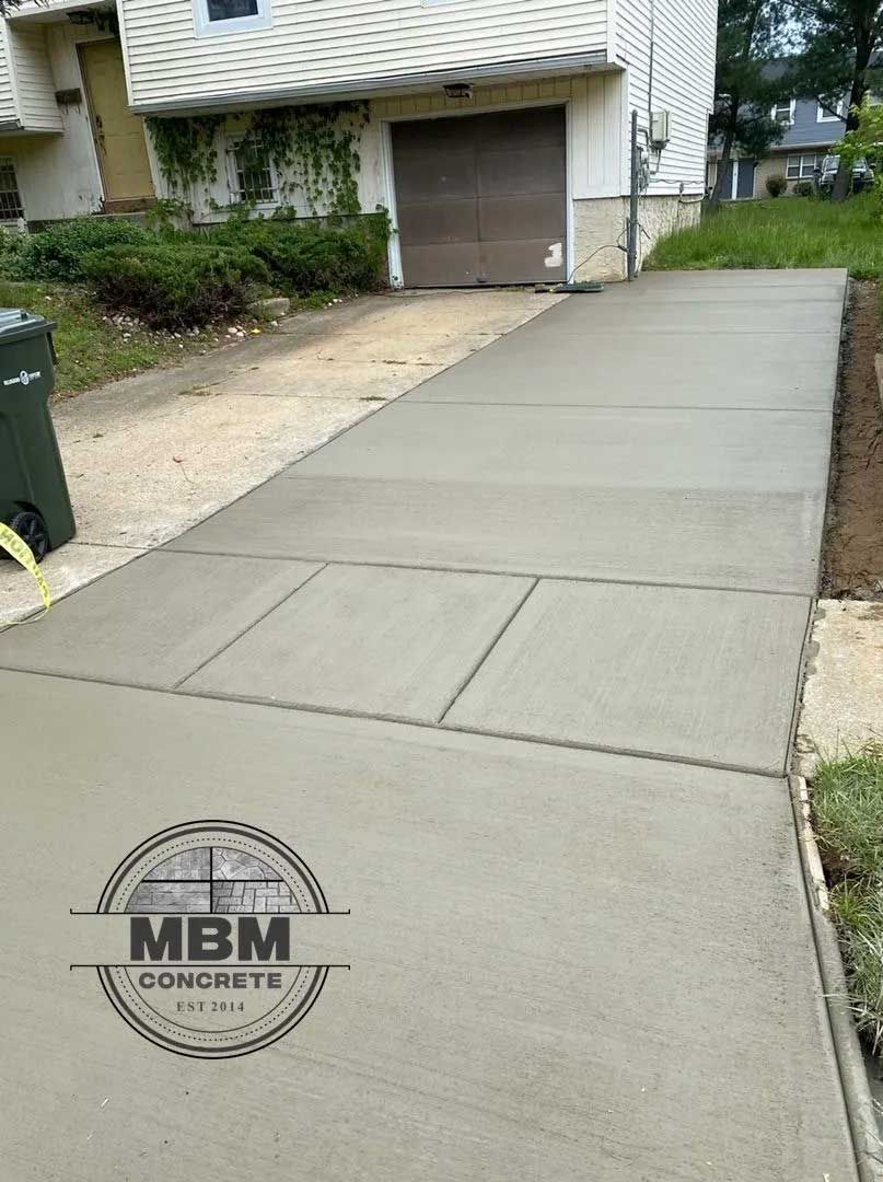 Freshly poured concrete driveway with a garage in the background.