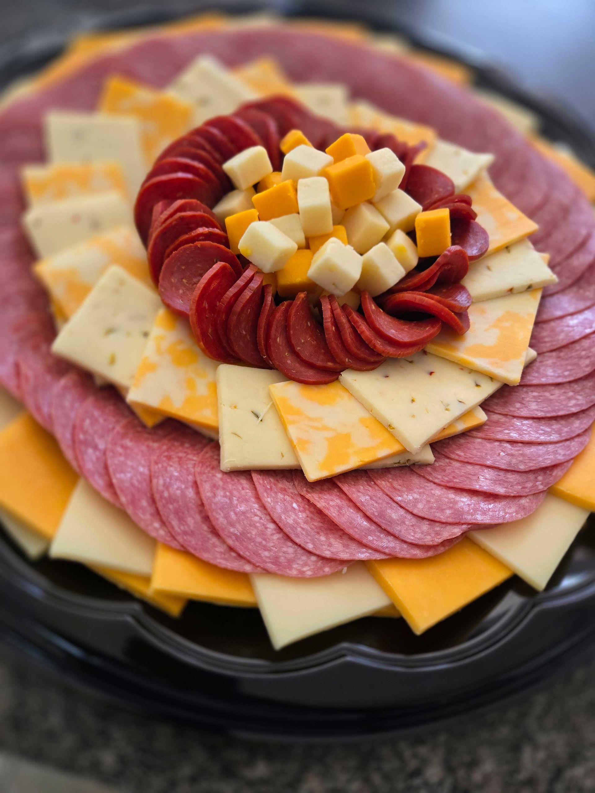 Charcuterie platter with pepperoni, cheese cubes, and stacked sliced cheeses and salami.