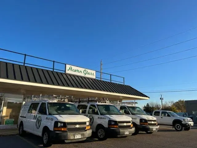 White vans parked outside a storefront with a green sign under a blue sky