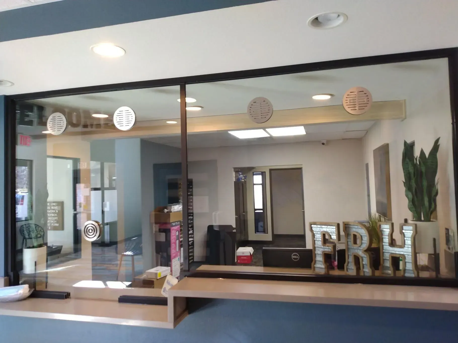 Modern lobby reception area with glass wall, front desk, and large decorative letters on the counter