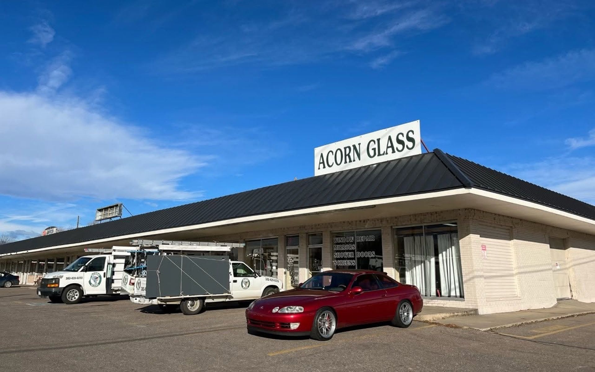 Corn glass storefront with white vans and a red car parked outside under a blue sky