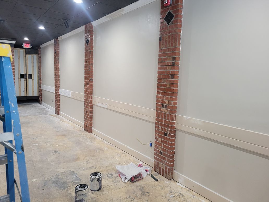 A ladder is sitting on the floor in a hallway next to a brick wall.