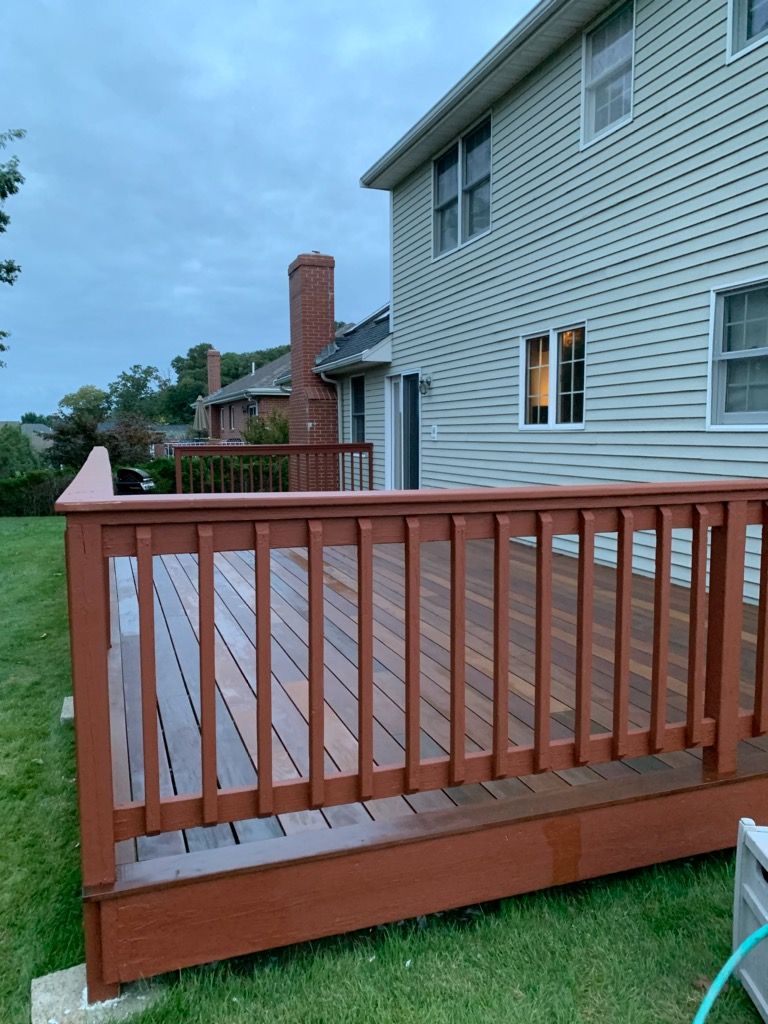 A large wooden deck is in front of a house.