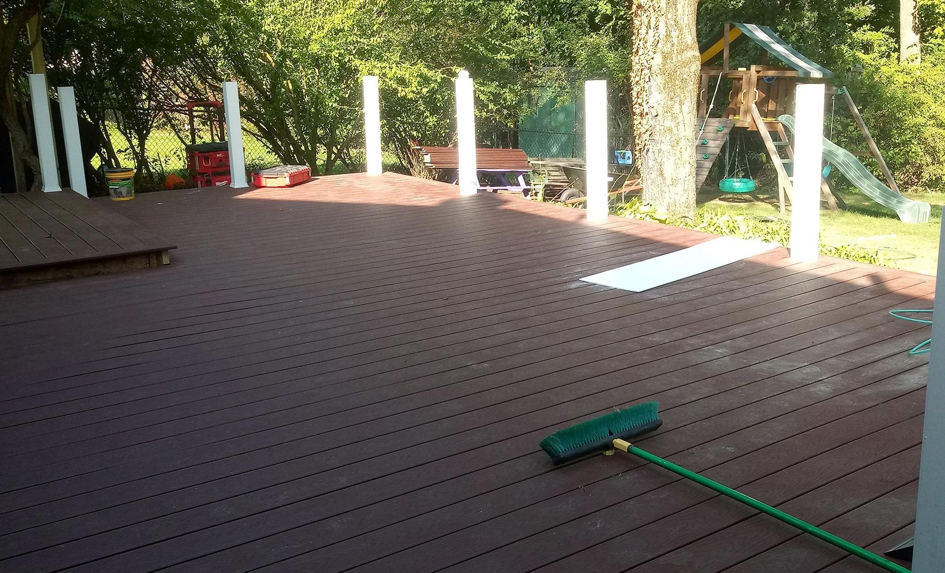 A deck with a broom and hose on it