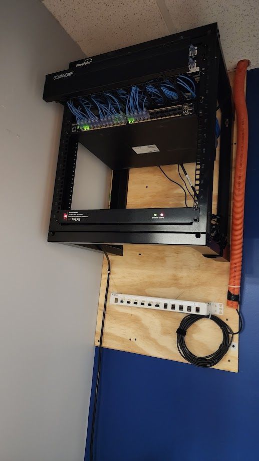 A server rack is sitting on top of a wooden table next to a blue wall.