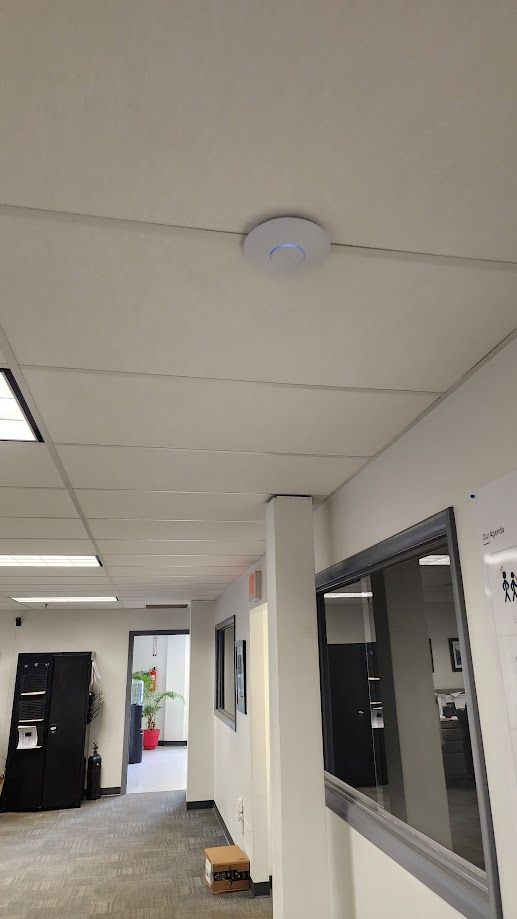 A hallway in an office building with a smoke detector on the ceiling.