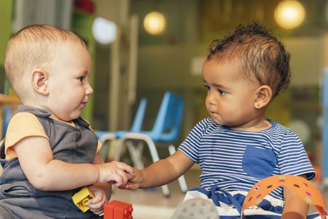 Two babies are holding hands