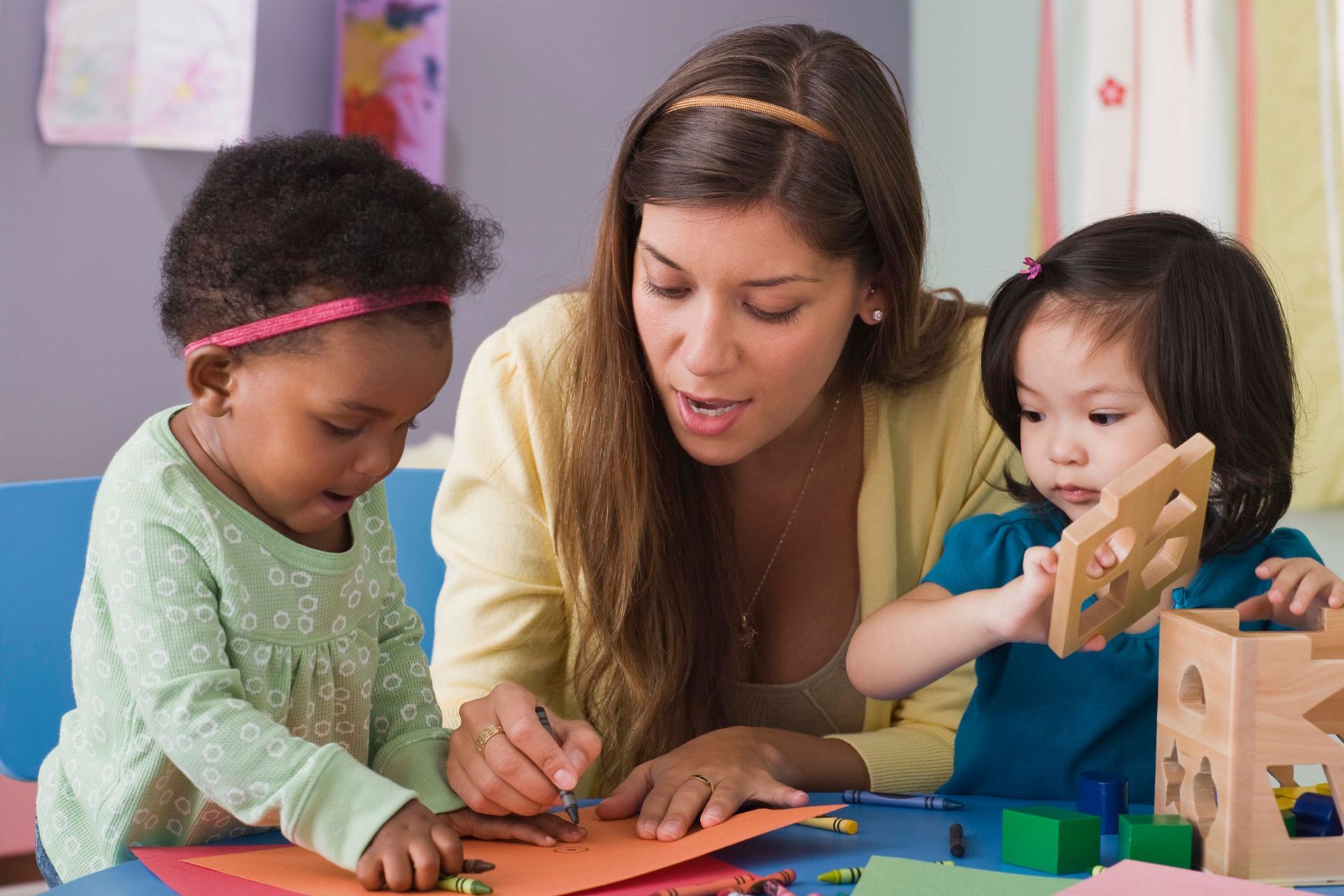 A woman is playing with two little girls at a table