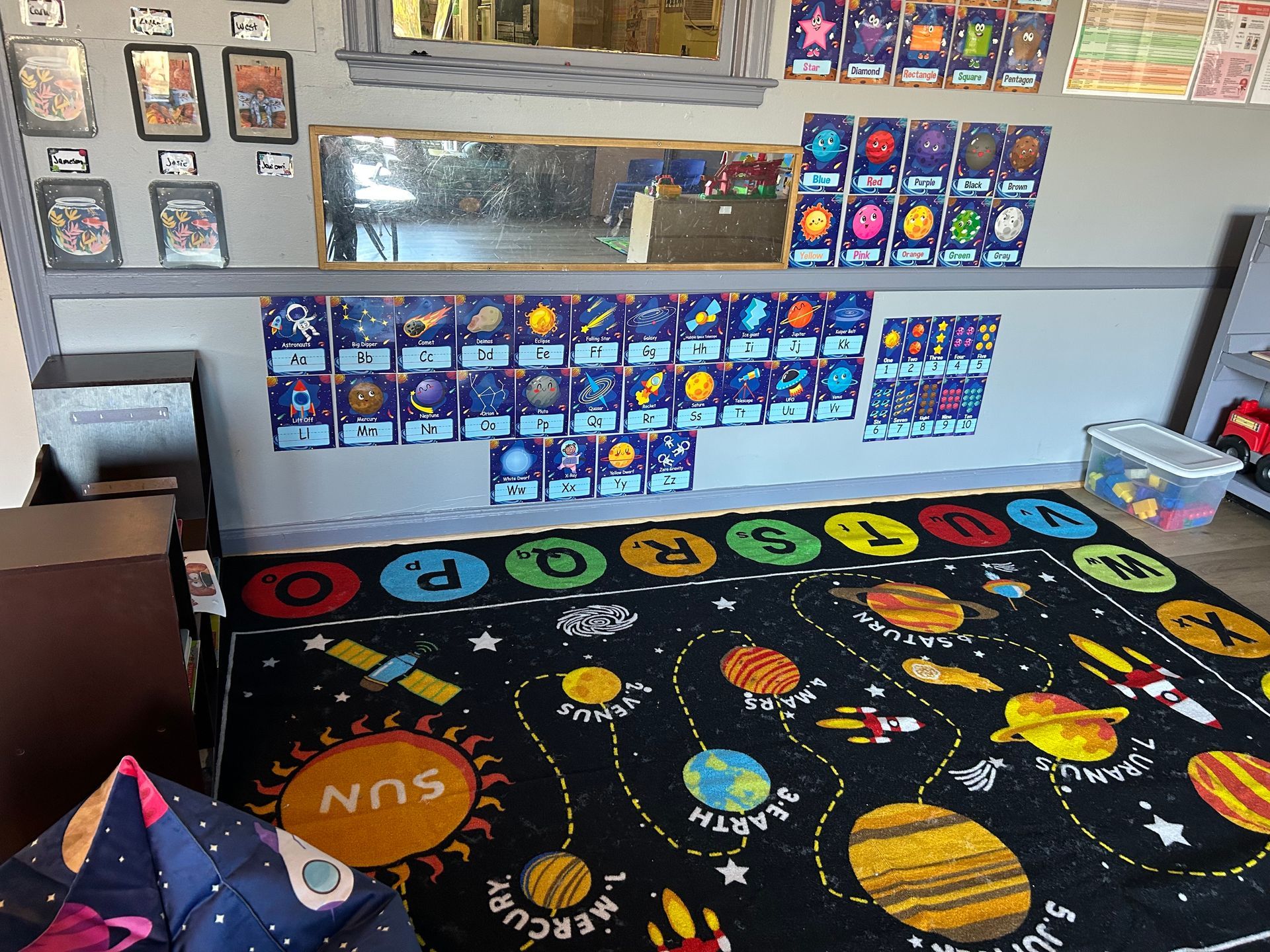 Ocean-themed classroom corner with alphabet, books, and green rug.