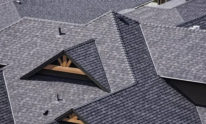 Gray shingled roof with multiple sections and a wooden triangular architectural detail.