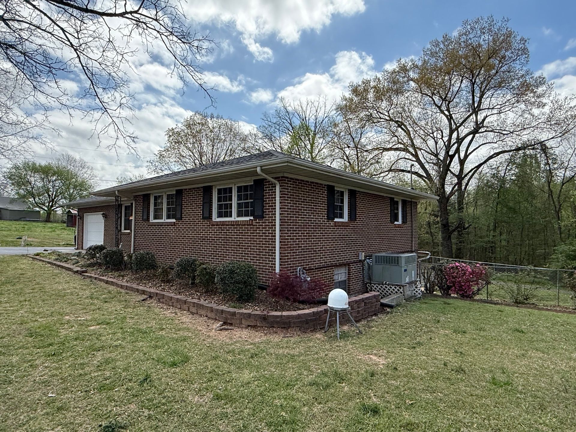 A single-story brick house with a unique, swirled dark-and-light-colored pattern on its exterior sits on a grassy lot.