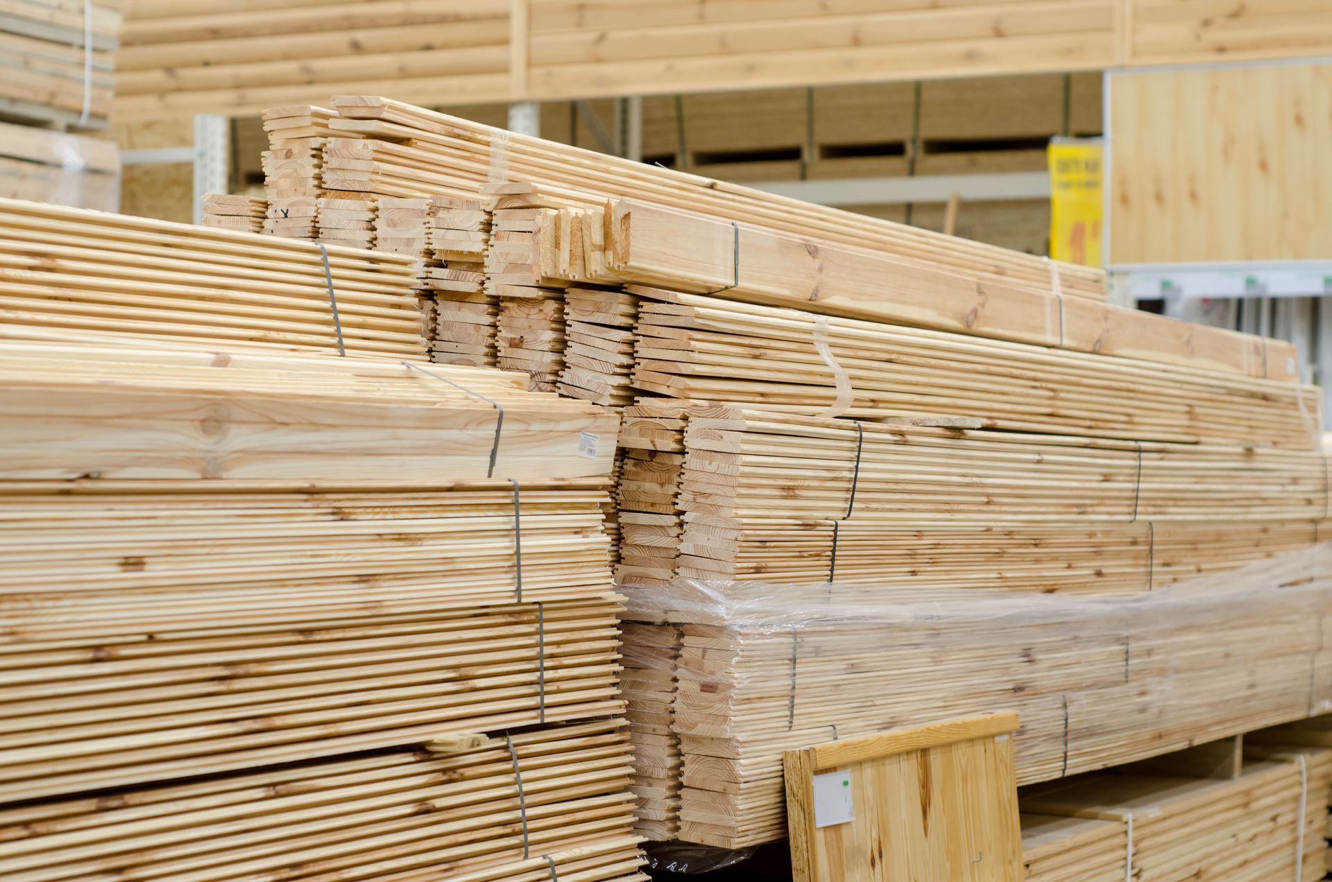 Stacks of light-colored, bundled wooden boards displayed in a store.