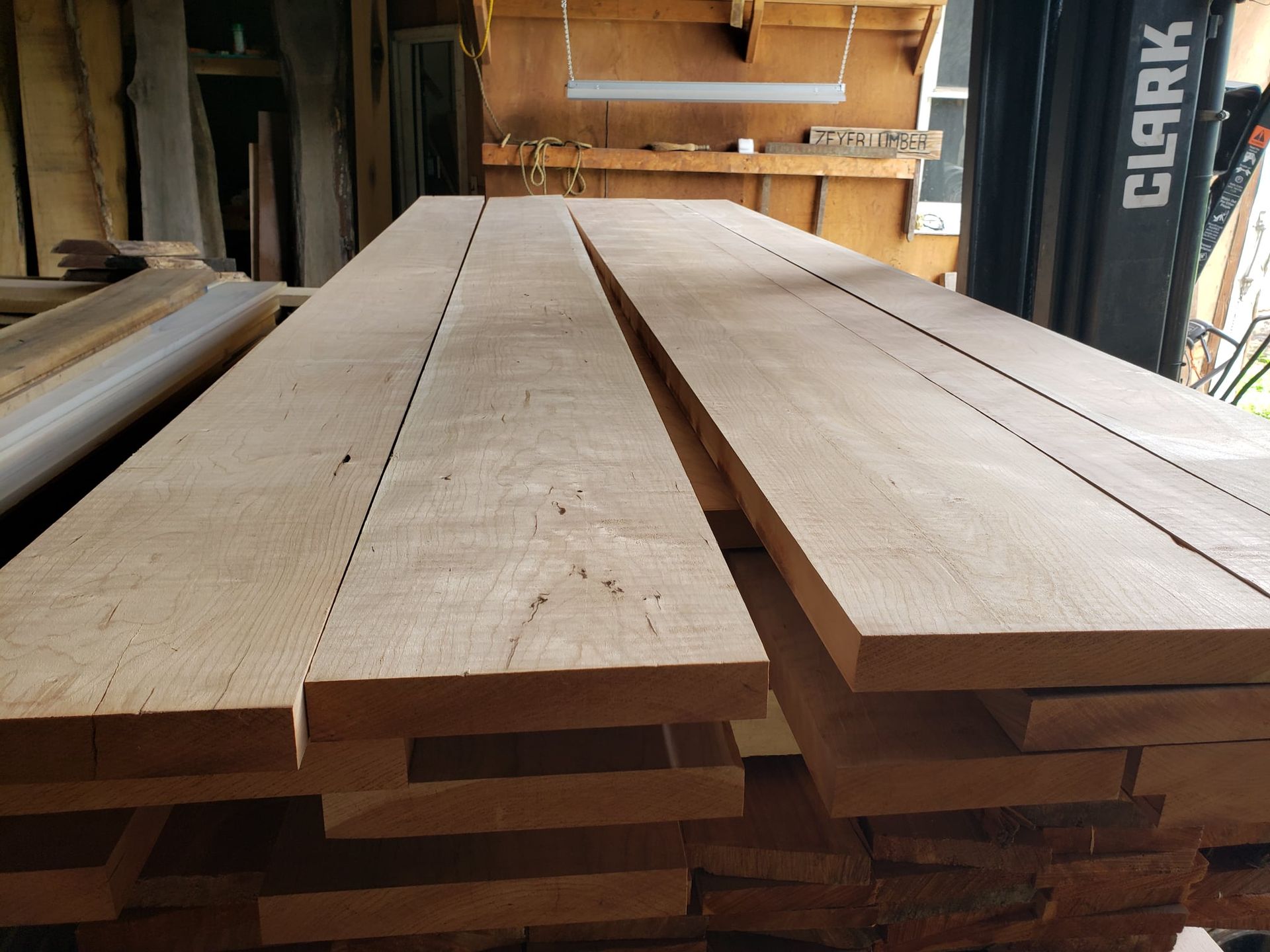 Two stacks of smooth, light-colored wooden planks neatly organized in a workshop or lumber yard.