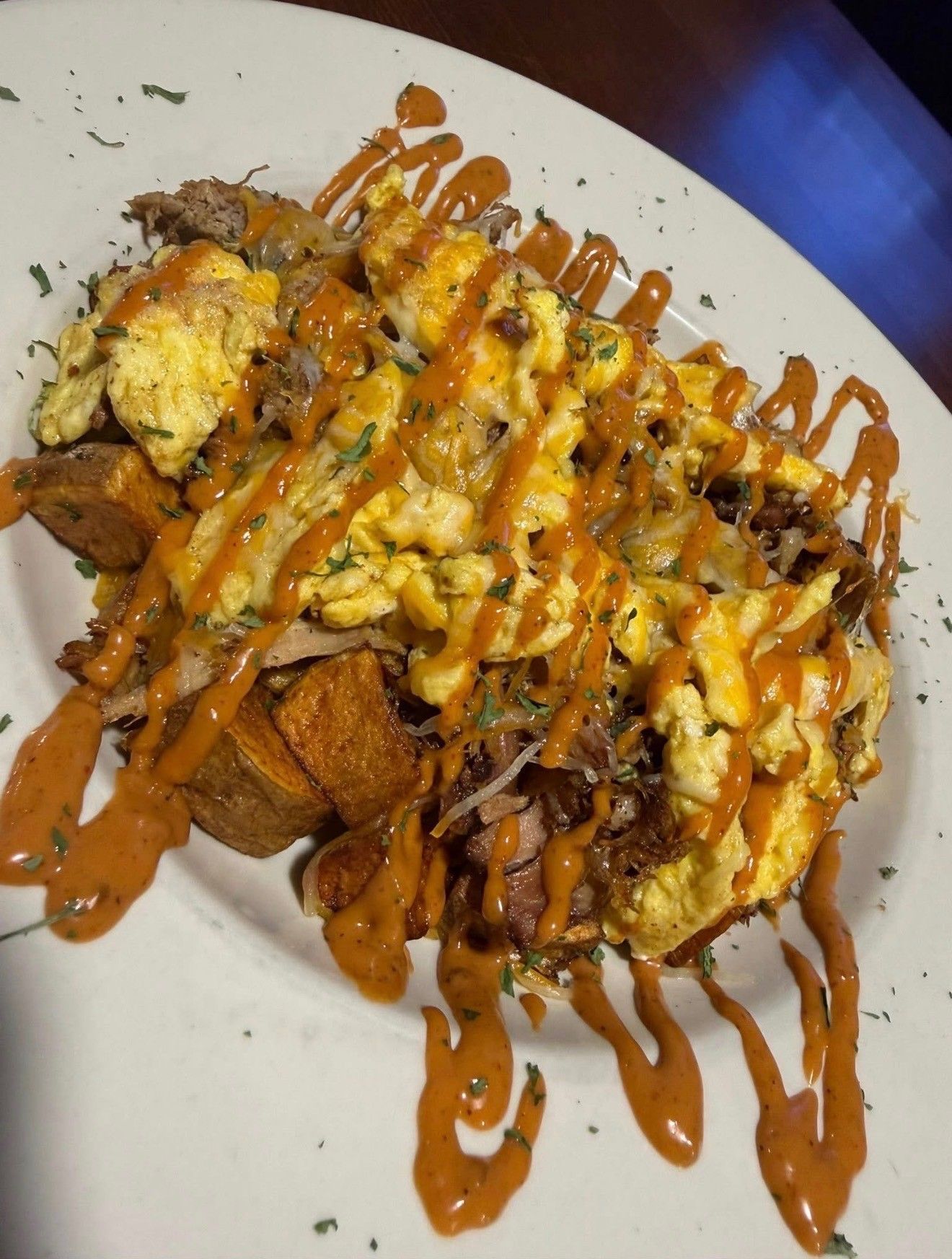 Scrambled eggs and fried plantains drizzled with orange sauce on a white plate
